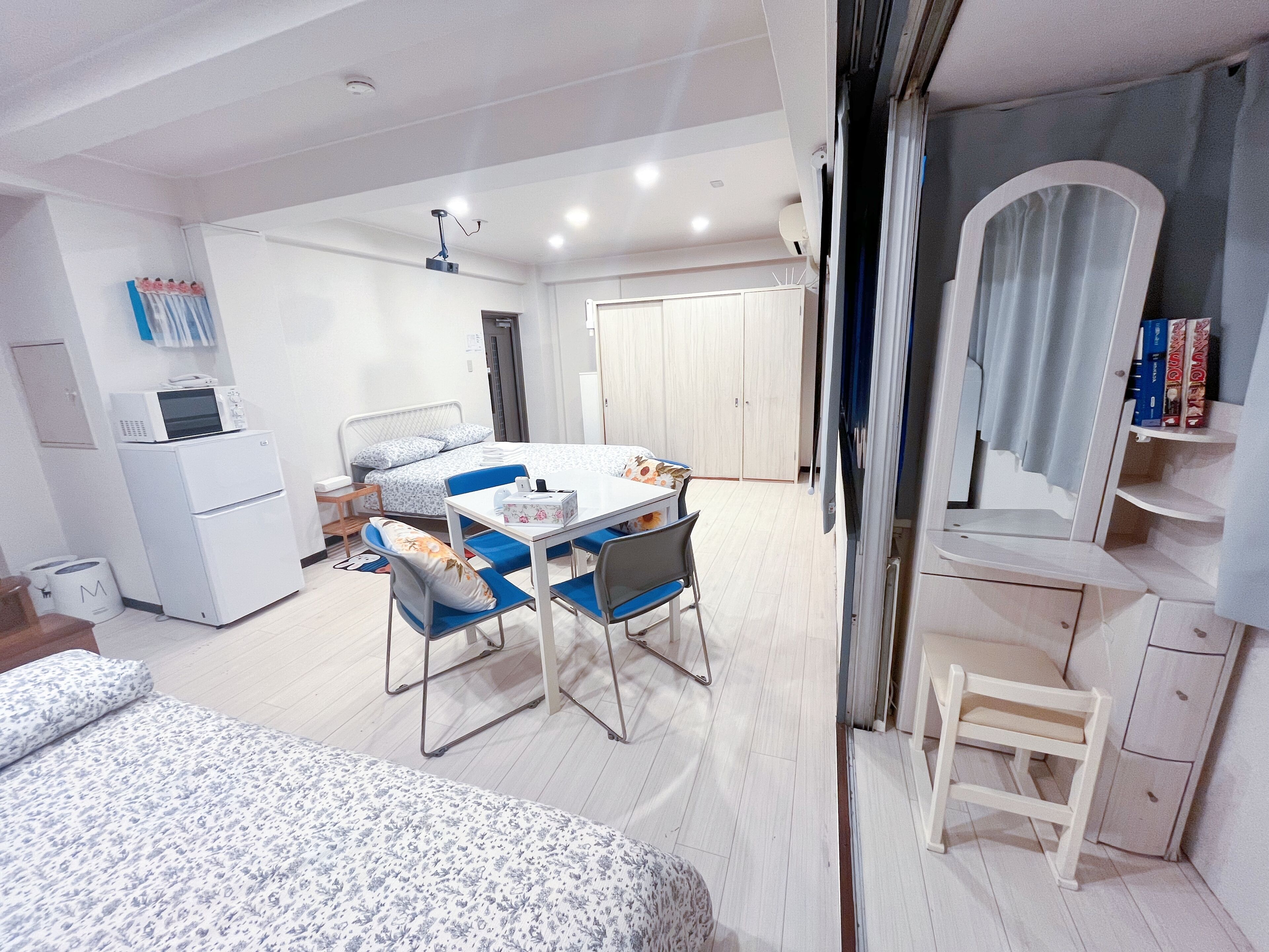 Een kleine hotelkamer met een bed, een bureau, een stoel, een kledingkast en een spiegel.