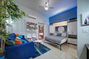 Ein modernes Schlafzimmer mit einem Bett, Nachttischen, einem Deckenventilator und einem großen Fenster.