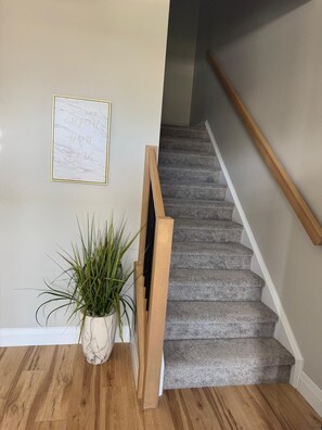 A staircase with a wooden handrail and carpeted steps.