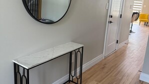 A hallway with a round mirror, a white console table, and a door leading to another room. - 5 Bedrooms deluxe, Hyde Park Mall and Western University area Sleep up to 10 (London)