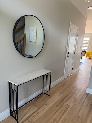 A hallway with a round mirror, a white console table, and a door leading to another room. - 5 Bedrooms deluxe, Hyde Park Mall and Western University area Sleep up to 10 (London)