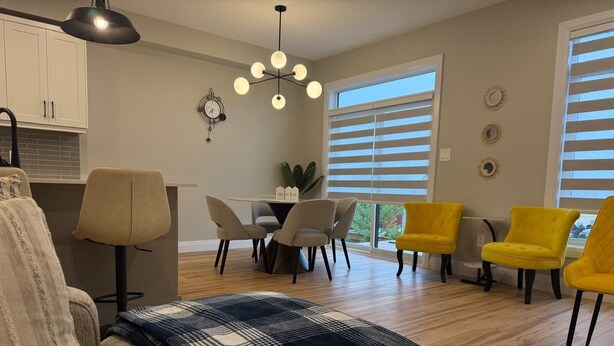 A modern living room with a sofa, chairs, a dining table, and a kitchen area. - 5 Bedrooms deluxe, Hyde Park Mall and Western University area Sleep up to 10 (London)