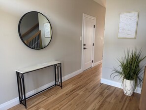 A hallway with a round mirror, a white door, a marble console table, and a potted plant. - 5 Bedrooms deluxe, Hyde Park Mall and Western University area Sleep up to 10 (London)