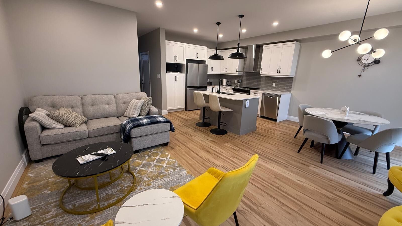 Un appartement moderne comprenant un salon, un coin repas, une cuisine et un petit îlot central.