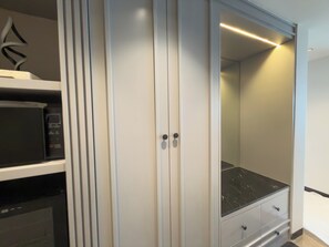 A modern closet with a microwave, a black countertop, and a sliding door.