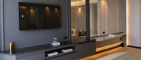 Un baño moderno con un espejo grande, un tocador con cajones y un banco.