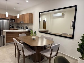 Eine moderne Küche mit Essbereich, inklusive eines großen Spiegels, Holzschränken und einem Edelstahlkühlschrank.