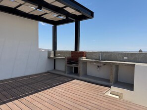 A rooftop terrace with a wooden deck, a barbecue grill, and a pergola structure. - Vista Cortés Ocean View | Walk to the Malecón (La Paz)