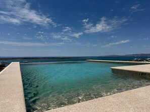 Un ciel d’un bleu limpide, avec une vue sur une mer calme et une terre lointaine.
