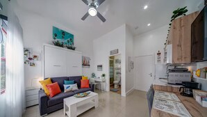 A modern living room with a sofa, coffee table, and a dining area with a kitchen counter. - ★The Riverwalk Getaway★ - Steps to DT - ♛Hot Tub (Fort Lauderdale)