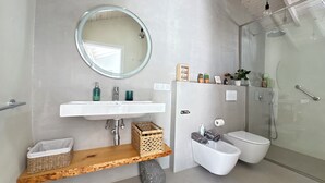A modern bathroom with a white sink, mirror, and shower. - Casita Coco – Your Lanzarote Home for Longer Stays | Work, Relax, Explore (Guatiza)