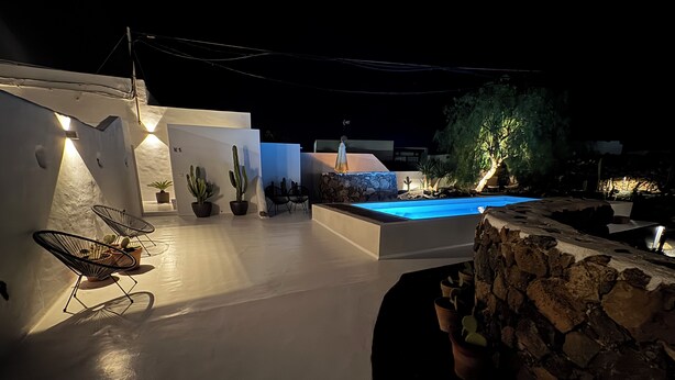 A modern outdoor area with a pool, stone walls, and potted plants. - Casita Coco – Your Lanzarote Home for Longer Stays | Work, Relax, Explore (Guatiza)