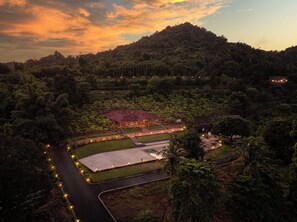 Un resort con una piscina grande, un espacio cubierto y vistas a una colina boscosa exuberante.