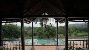 Un espacio al aire libre cubierto con una piscina, rodeado de follaje y vistas a un paisaje montañoso.
