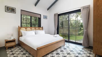 Une chambre à coucher avec un lit en bois, une table de chevet, une fenêtre avec des rideaux et une vue sur la verdure à l’extérieur.