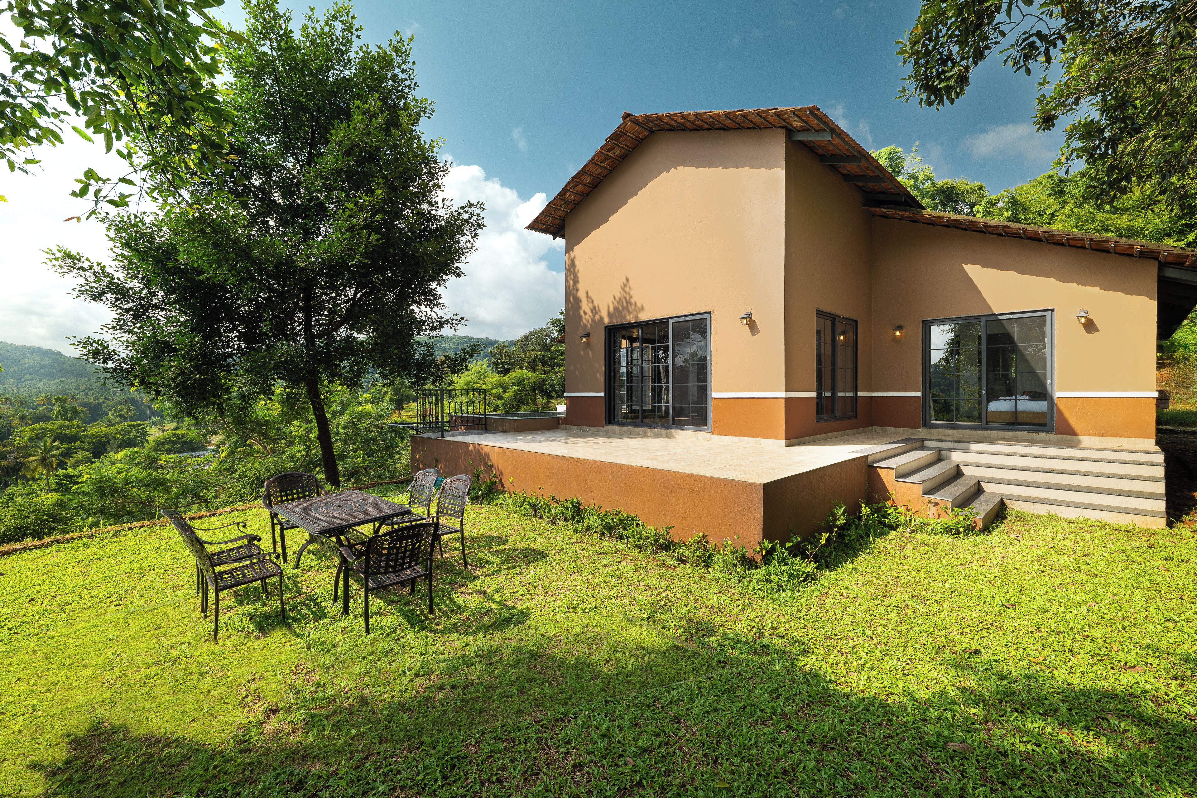 A two-story house with a patio, a table, and chairs.