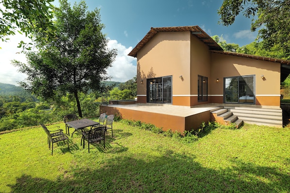 A two-story house with a patio, a table, and chairs.