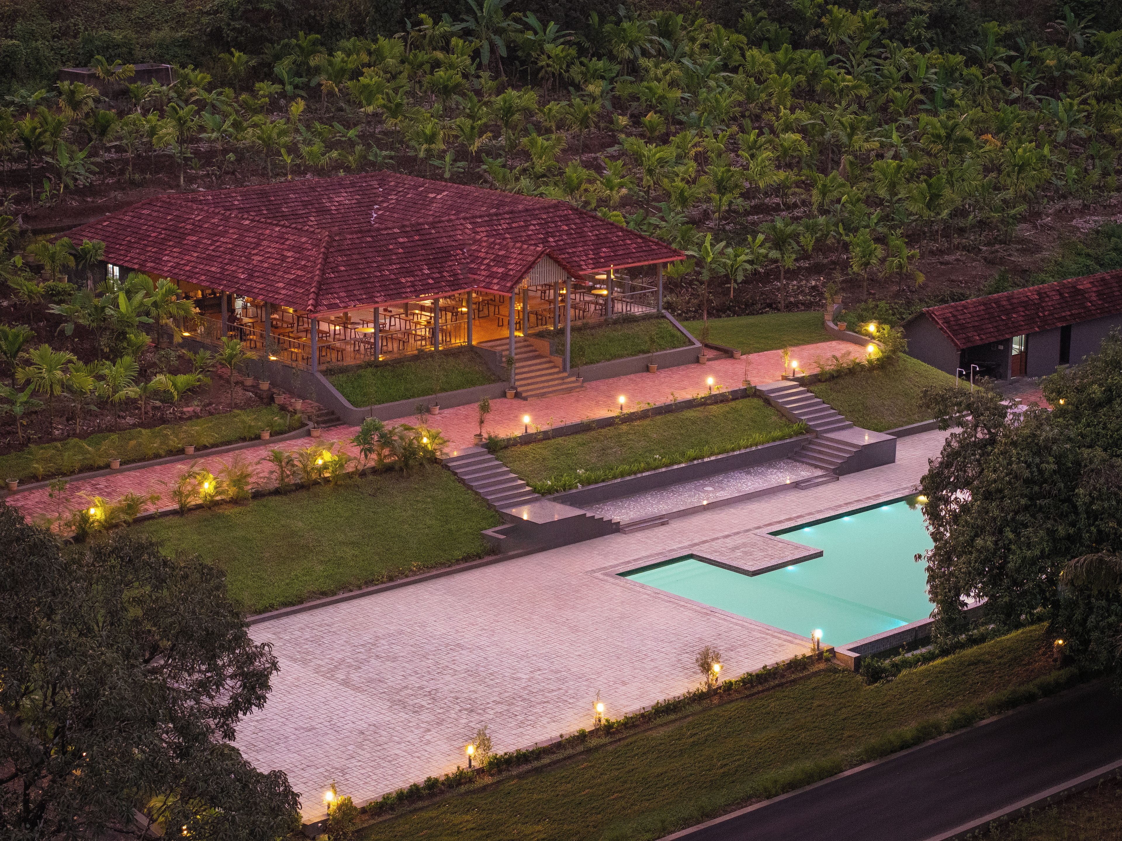 A resort with a swimming pool, a covered dining area, and a well-maintained garden.