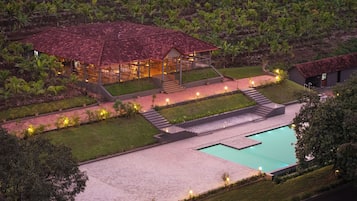 A resort with a swimming pool, a covered dining area, and a well-maintained garden.
