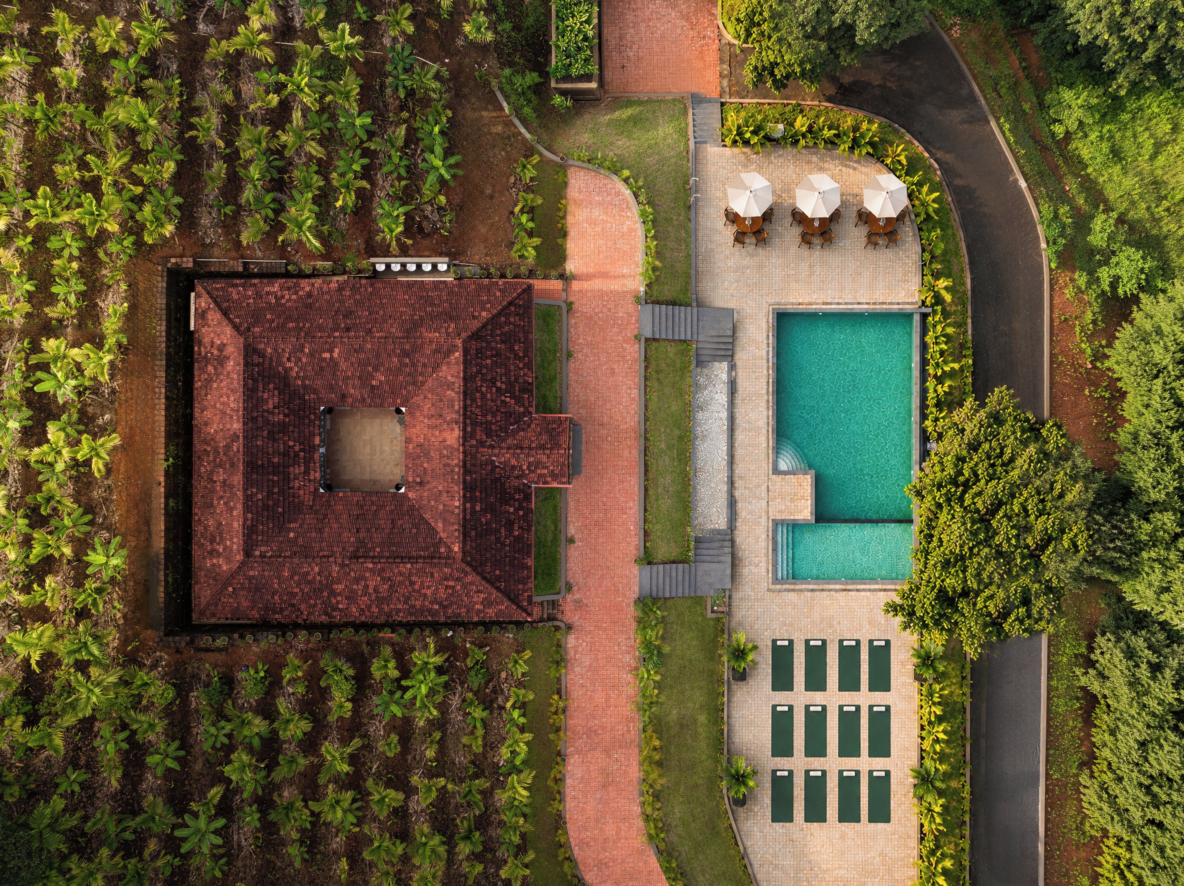 An aerial view of a property with a swimming pool, outdoor seating area, and a garden.