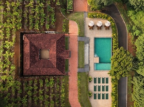 An aerial view of a property with a swimming pool, outdoor seating area, and a garden.