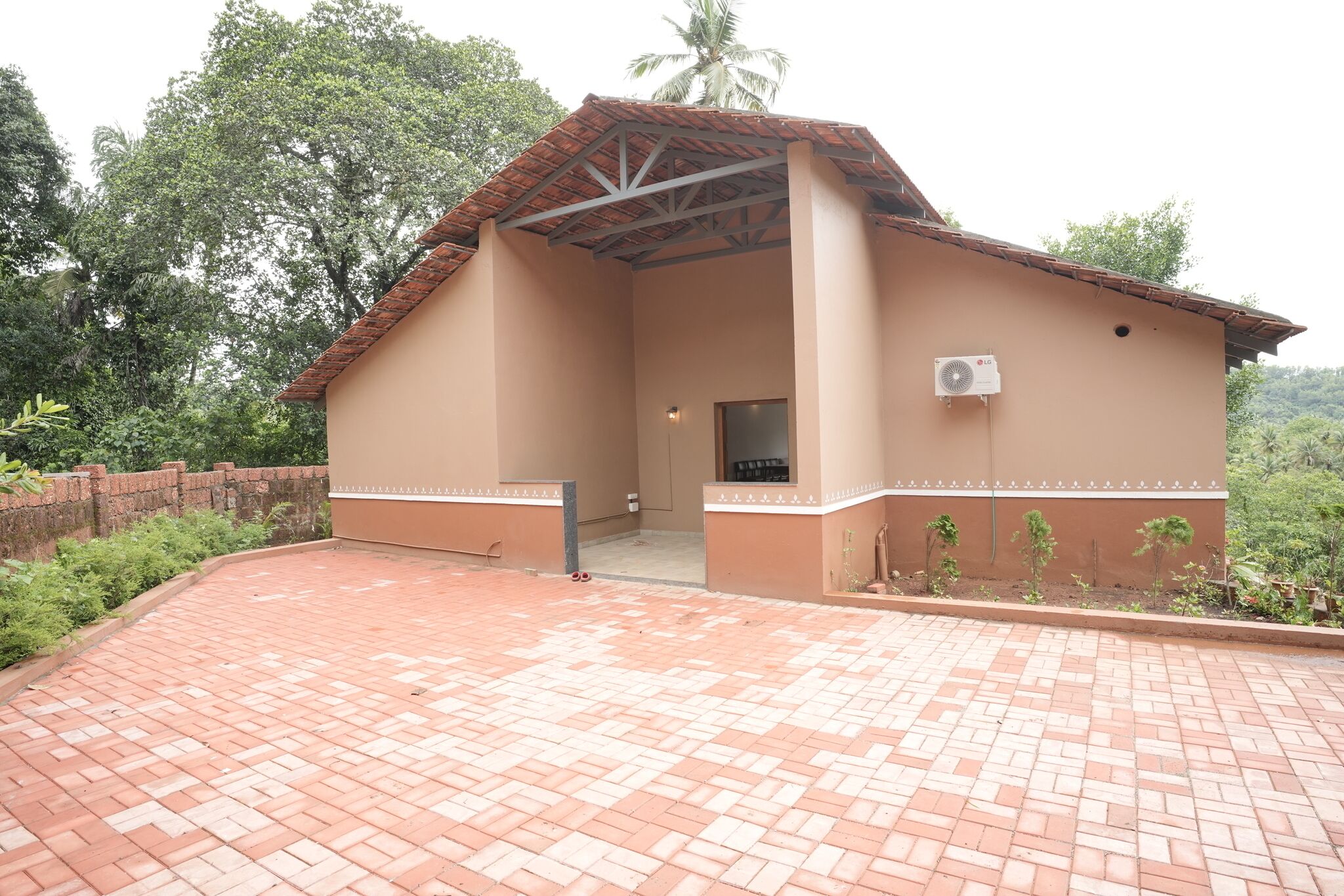 A building with a tiled roof, a brick-paved entrance, and a small garden area.