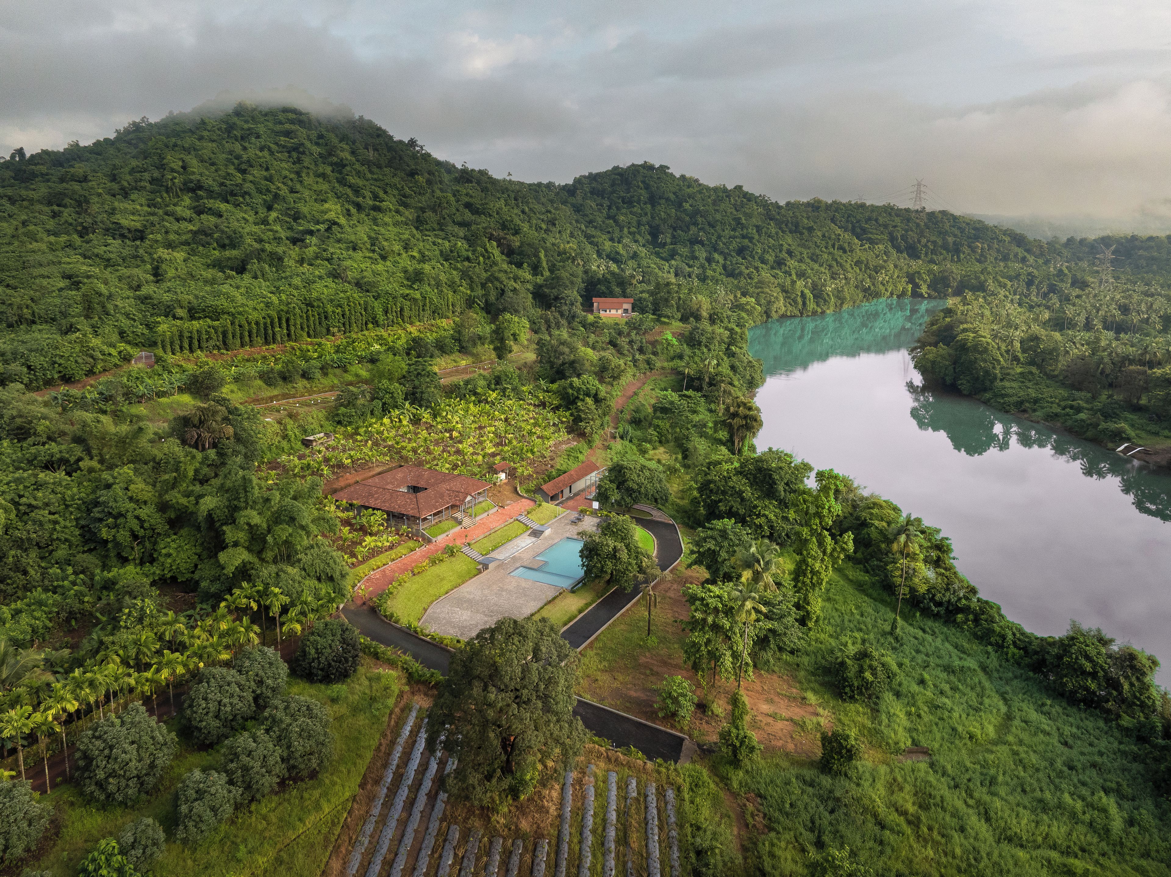 Un paisaje exuberante con un río, un edificio pequeño y una piscina.