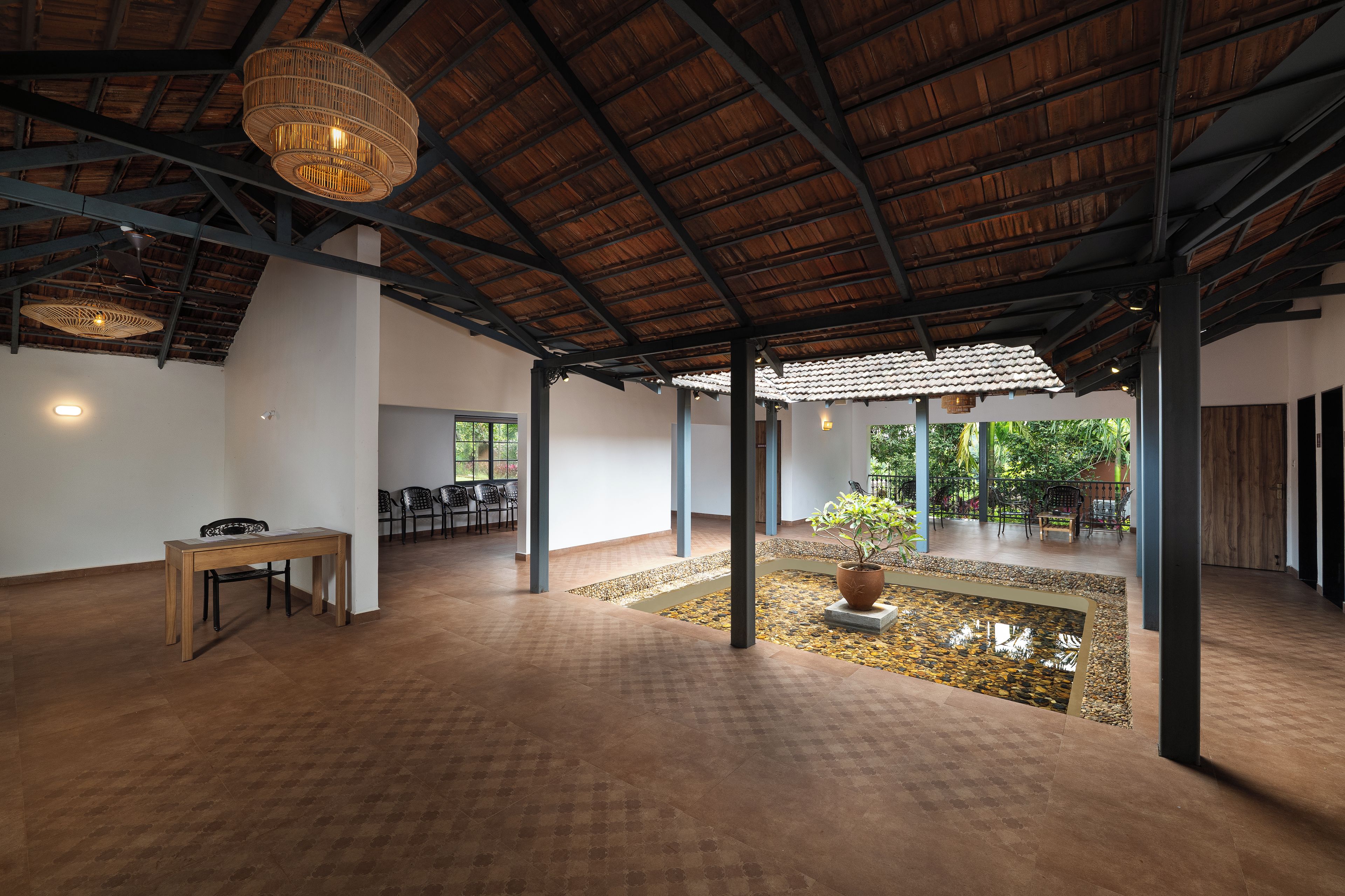 A spacious indoor area with a high ceiling, a seating area with chairs, a small water feature, and a table.