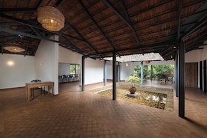 A spacious indoor area with a high ceiling, a seating area with chairs, a small water feature, and a table.
