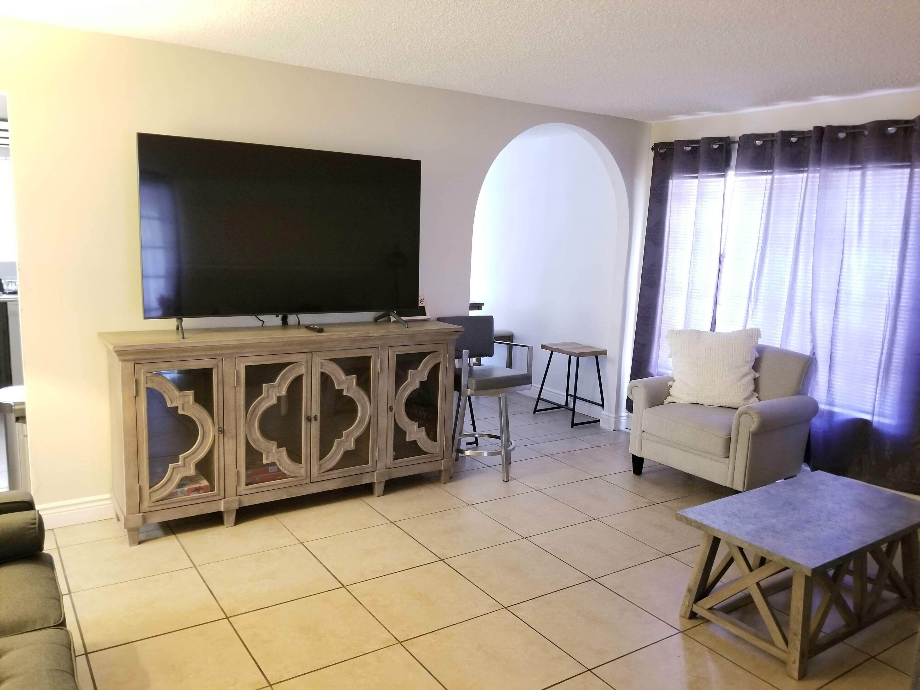 Una sala de estar con televisión de pantalla plana, sofá, mesa de centro y un aparador.