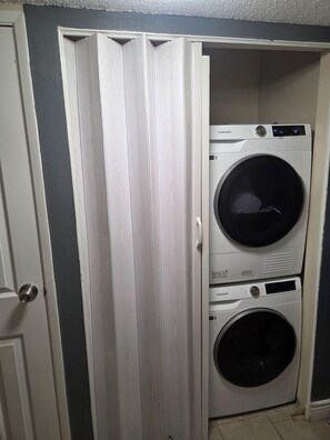 A laundry room with two stacked washing machines and a door. - 3-bedroom house in tranquil Las Vegas with cool vibes (Las Vegas)
