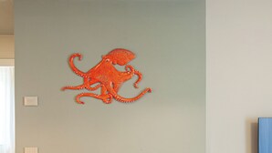 Uma sala de jantar com mesa de madeira, seis cadeiras e um objeto decorativo na parede.
