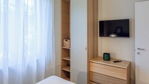 Quarto com cama, guarda-roupa, televisão e mesa de cabeceira com controle remoto.