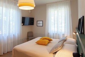 Ein Hotelzimmer mit einem Bett, einem Sessel, einem Fernseher und einem Wandbild.