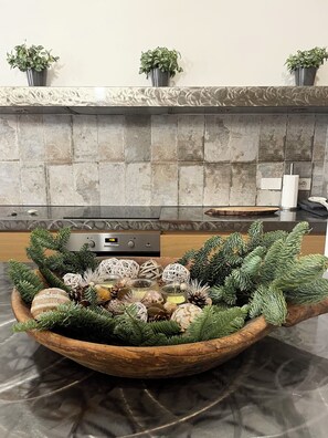 A kitchen with a stone backsplash, a wooden bowl with decorative items, and three potted plants on the counter. - Bright and quiet, located between Campo de Fiori and Piazza Farnese. (Roma)