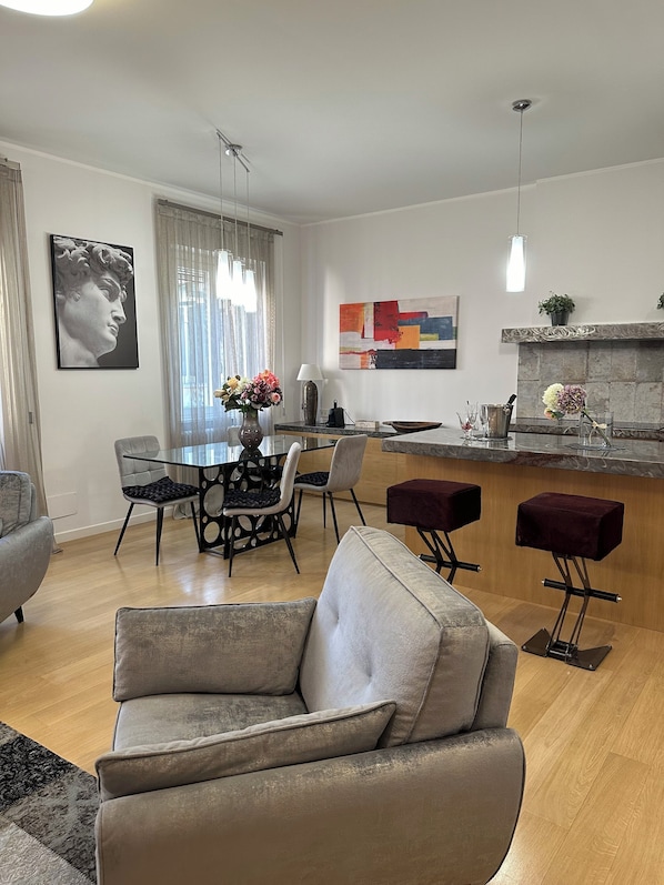Uma sala de estar moderna com sofá, espaço de jantar e balcão de cozinha.