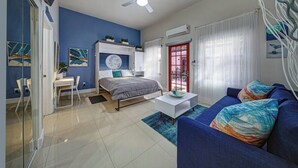 Una sala moderna con una cama, un sofá, una mesa de centro y un escritorio.