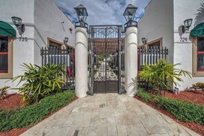 A gated entrance with a metal gate, two columns, and a paved pathway leading to a building with the numbers 735 and 729 on the walls. - Stylish Studio Oasis - Walk to Downtown - ♛Hot Tub (Fort Lauderdale)