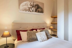 Ein Schlafzimmer mit einem gesteppten Kopfteil, einem Bett mit weißer Bettwäsche und vielen Kissen, einem Wandbild von Eisbären und Nachttischlampen.