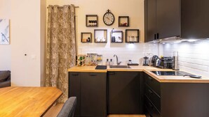 Una cocina compacta con una mesa de comedor de madera, muebles negros y salpicadero blanco de azulejos.
