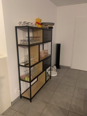 A multi-tiered metal and wood shelf unit with glassware and plates. - 3-bedroom house with a pool, in a quiet neighborhood (Saint-Jean-de-Monts)