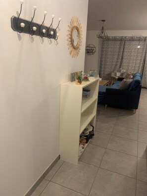 Ein Wohnzimmer mit einer Couch, einem Couchtisch und einem Fernseher. Eine Wandregal ist mit Dekorationen ausgestattet.