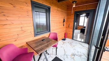 A wooden interior with a table and chairs, a window, and a door leading outside.