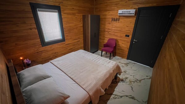 Una habitación con paneles de madera, una cama, una silla, un armario y una puerta.