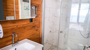 A modern bathroom with a wooden vanity, a glass shower enclosure, and a separate toilet.
