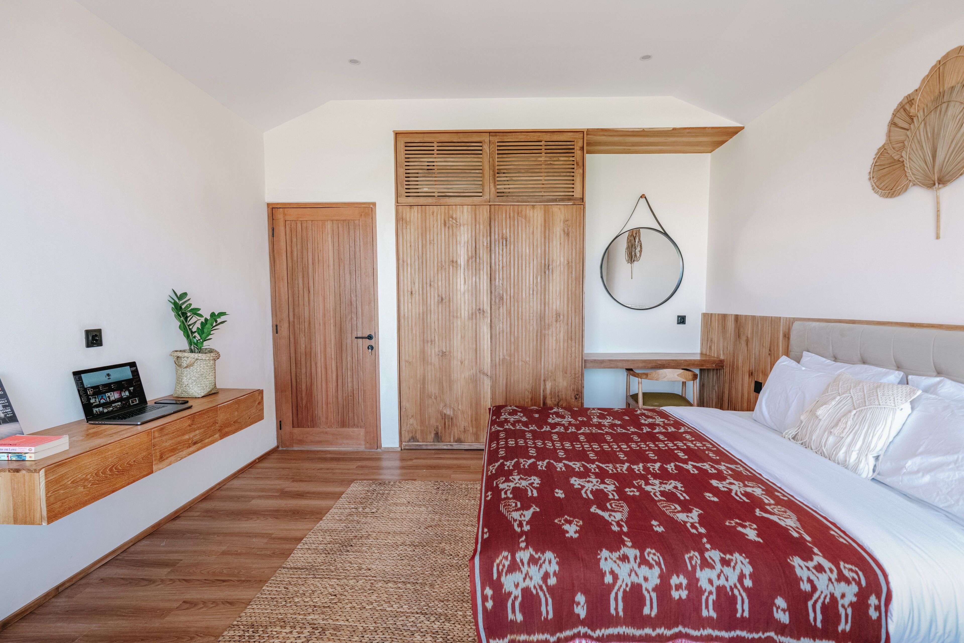 Un dormitorio con cama, escritorio, armario y una planta.