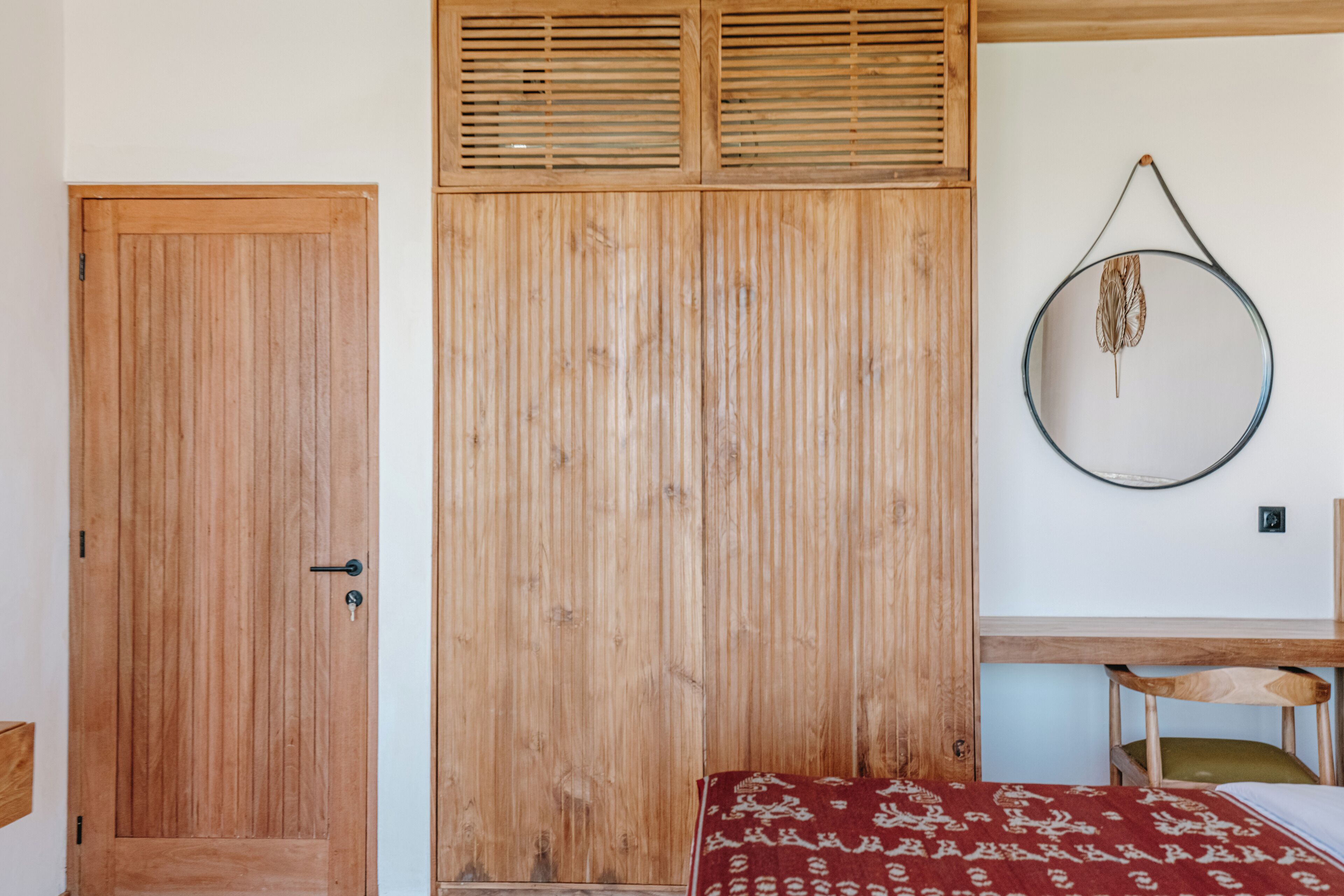 Una habitación con un armario de madera, una cama con colcha estampada y un adorno circular en la pared.