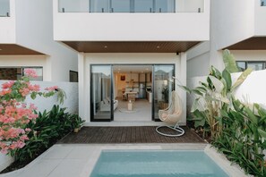 A modern residential building with a glass door entrance, a small outdoor pool, and a variety of plants. - Brand New 2BR Villa Private Pool Rooftop (Munggu)