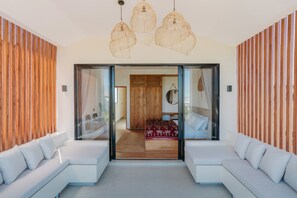 A modern interior with a sofa, a bed, and a view through a glass door. - Brand New 2BR Villa Private Pool Rooftop (Munggu)