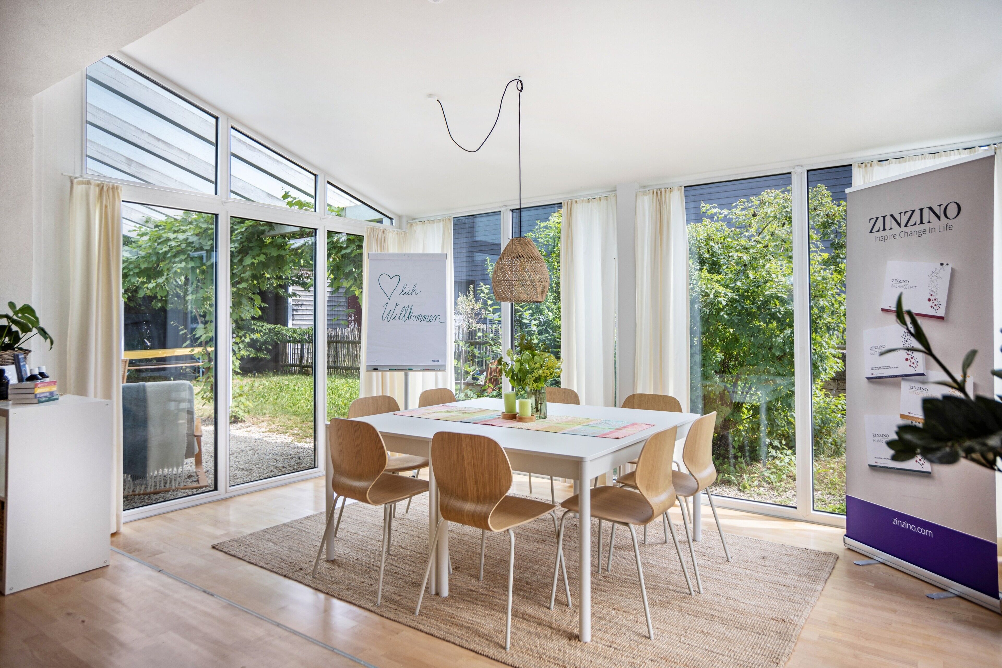 A modern conference room with a large table, chairs, a whiteboard, and a banner for ZINZINO.